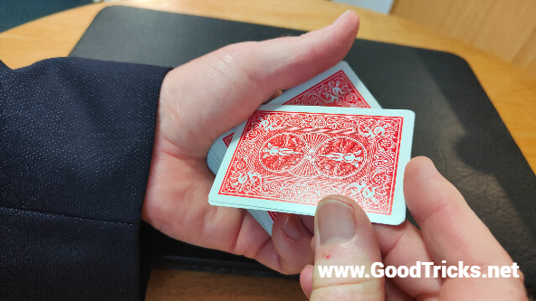 Two cards are held in place together and pivoted against the fleshy part of your thumb.